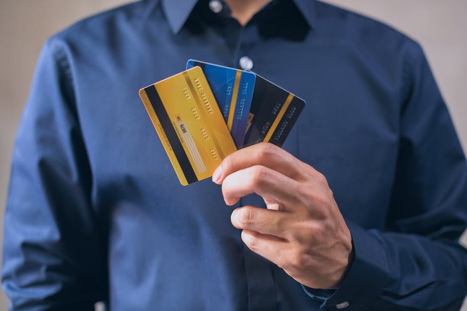 Person holding three credit cards, symbolizing finance, security, and e-commerce.
