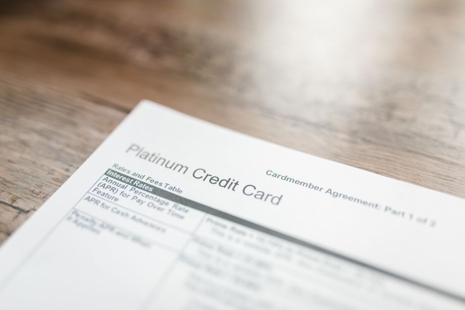 Close-up of a platinum credit card document with interest rates table on a wooden surface.