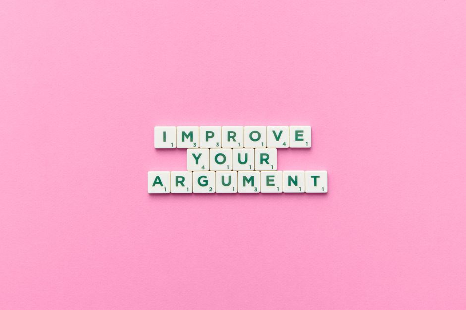 Scrabble tile letters spelling 'Improve Your Argument' on a pink background.