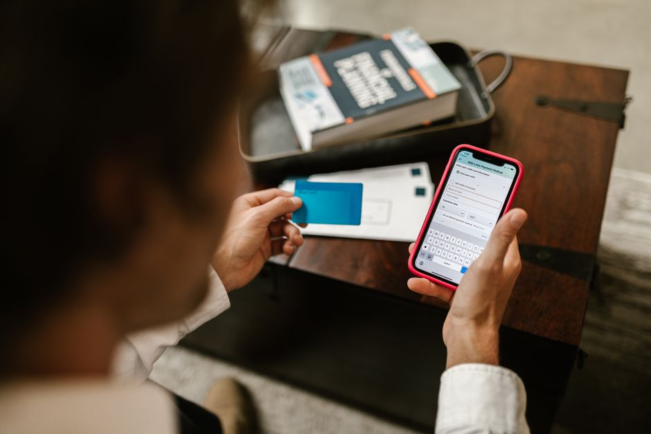Person making an online payment using a smartphone and credit card indoors.