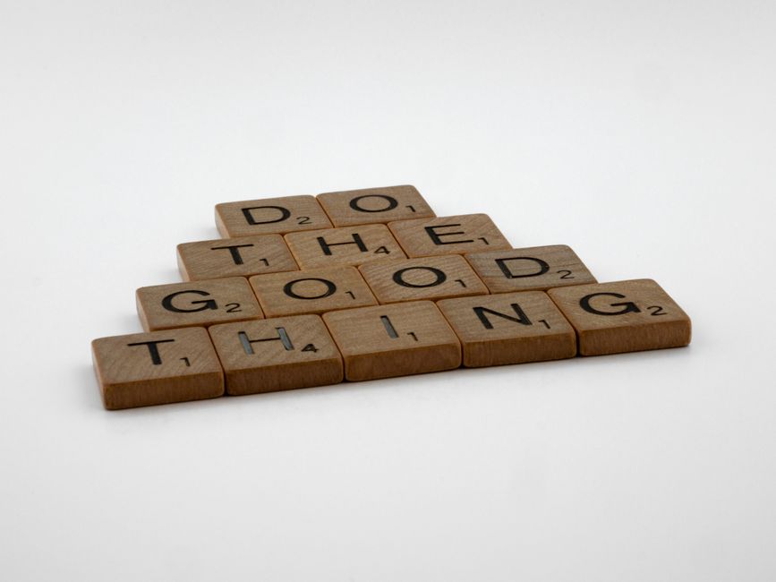 Scrabble tiles arranged to spell 'Do the good thing' on a white surface.