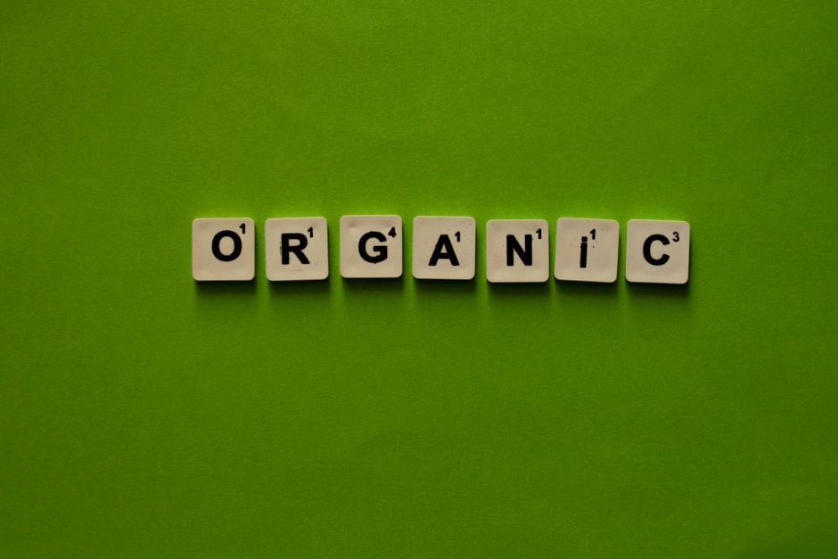 Scrabble tiles spelling 'Organic' on a vibrant green background, emphasizing sustainability.