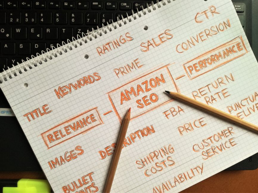 Notebook with handwritten Amazon SEO strategy topics highlighted on a keyboard.