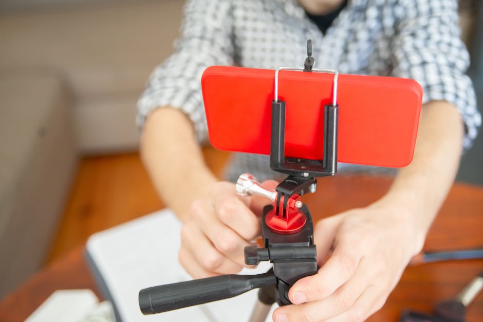 Close-up view of a person setting up a smartphone on a tripod indoors.