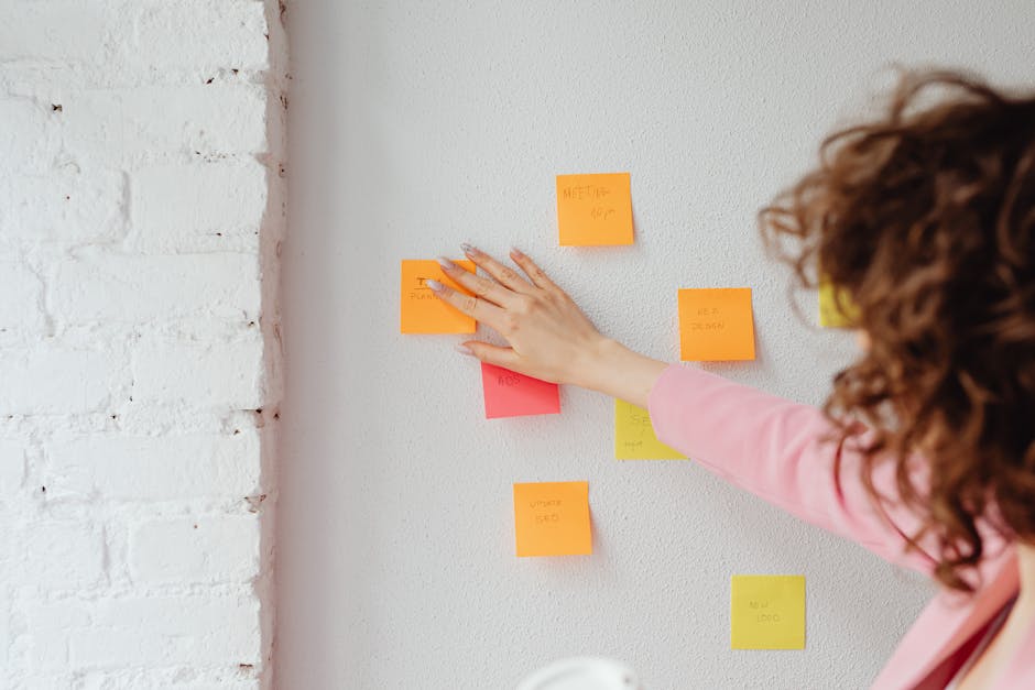 A woman planning ideas with colorful sticky notes on a wall. Ideal for conceptual and organizational themes.