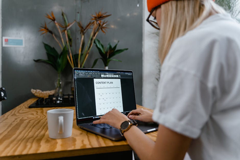 Focused woman typing on laptop while creating a content plan in a modern workspace.