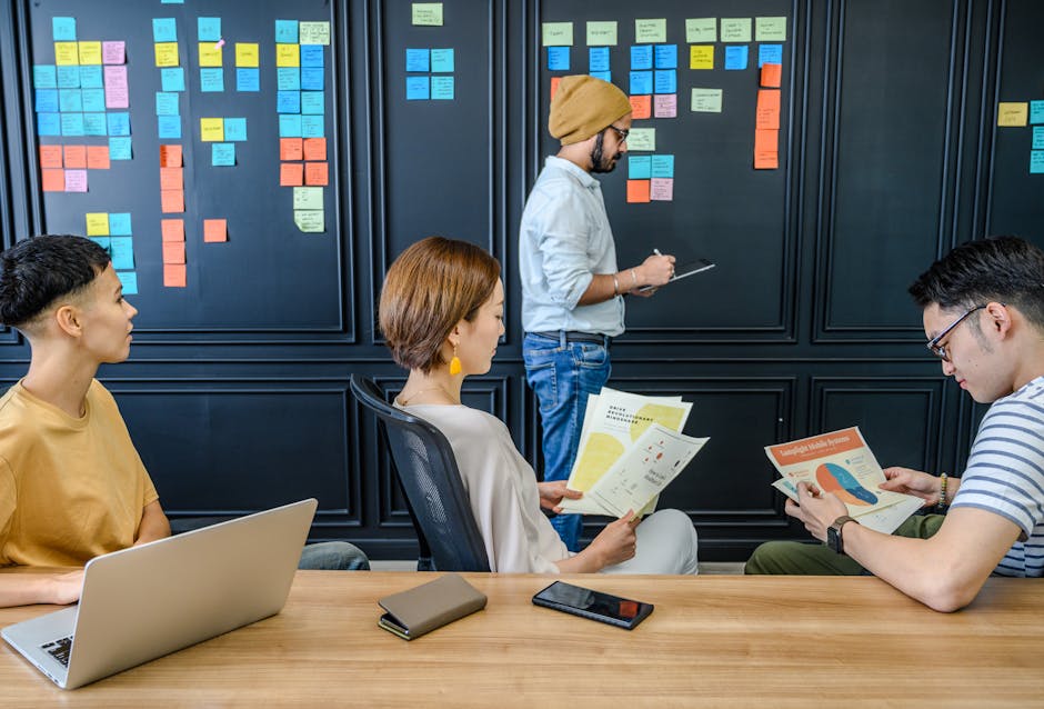Group of colleagues engaged in a brainstorming session with sticky notes and documents in a modern office setting.