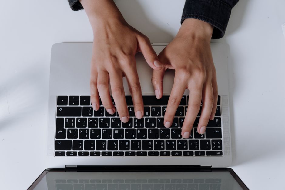 Top view of hands typing on a laptop keyboard, showcasing modern technology in use.