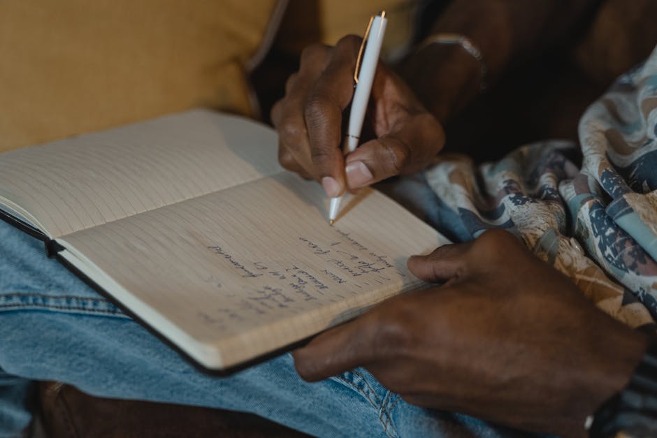 A detailed close-up of hand writing notes in a lined notebook using a white pen indoors.