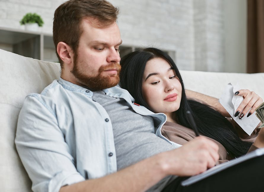 A relaxed interracial couple sitting indoors, reviewing documents together.