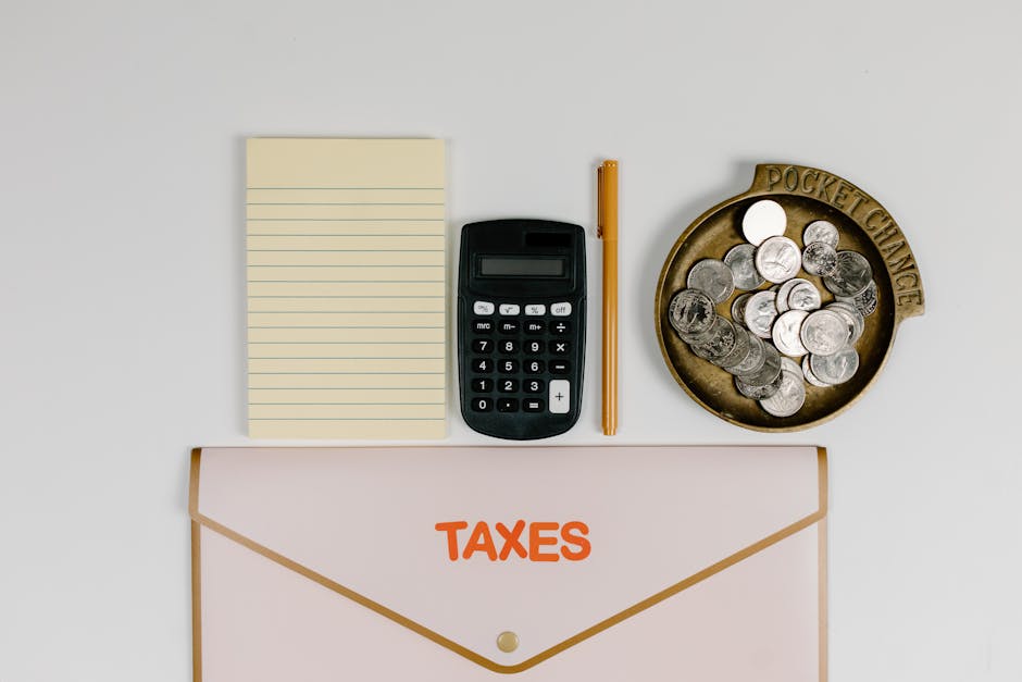 A flat lay of tax preparation essentials: calculator, coins, notepad, pen, and folder.
