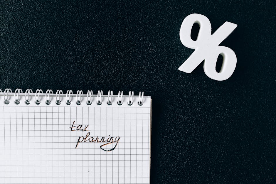 A notebook with 'tax planning' written on a grid paper next to a percent symbol on a black background.