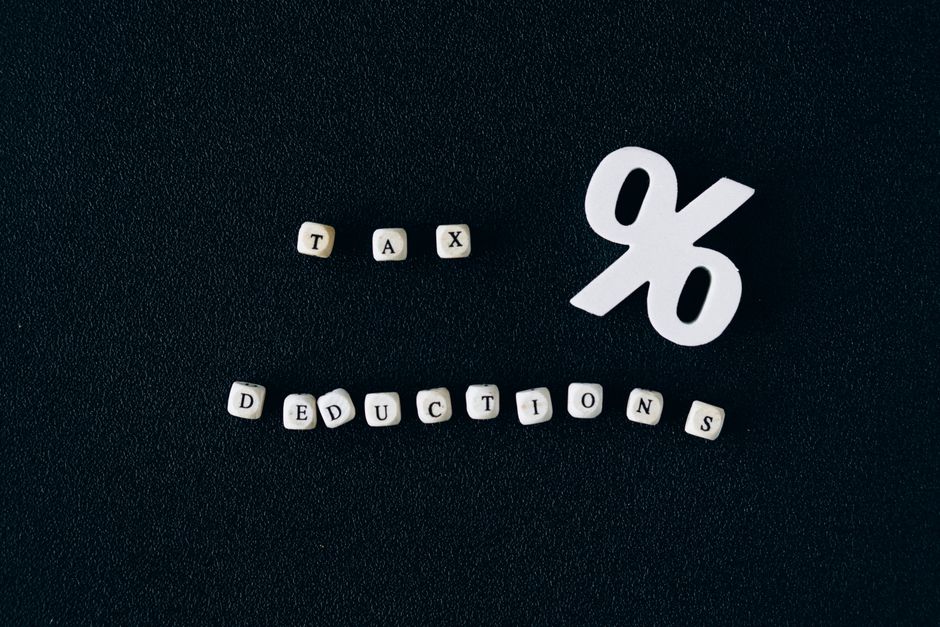Conceptual image of tax deductions with alphabet blocks and percent symbol on black surface.