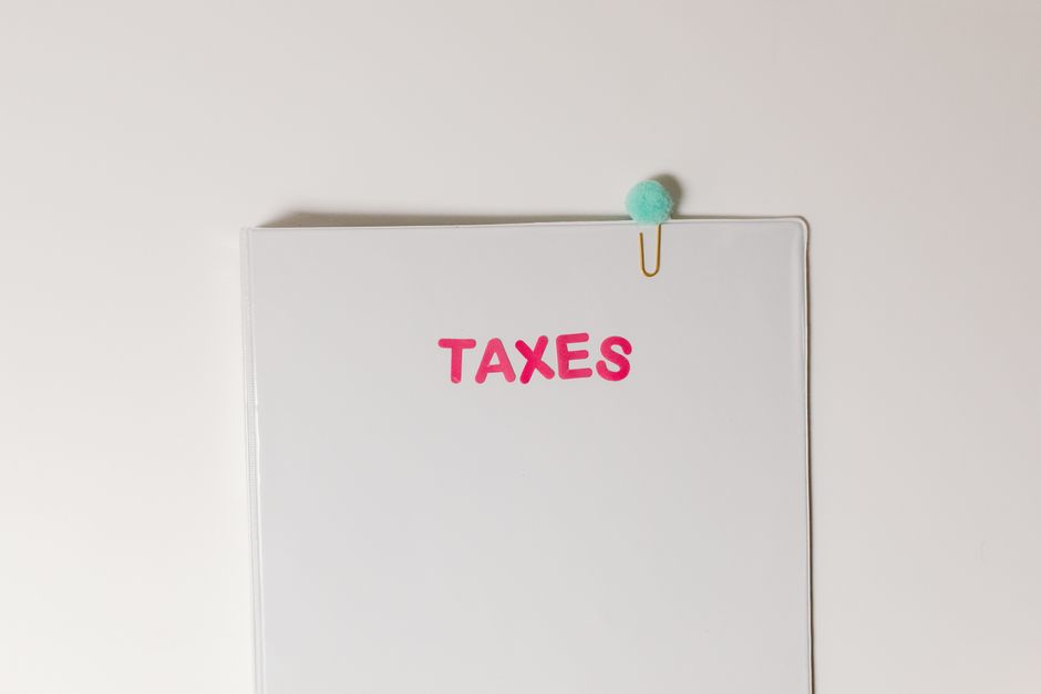 Close-up of a tax file with a pink 'TAXES' label and a paperclip, offering copy space and a conceptual minimalist design.
